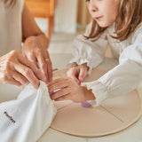 Close up of woman and young girl putting pieces from the PlanToys wooden Mandala toy blocks set into the organic cotton carry bag