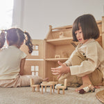 Two children sat on the floor playing with the PlanToys wooden Victorian furniture dollhouse set