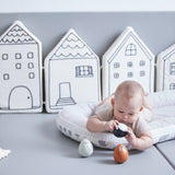 Baby laying on a white cushion looking at the PlanToys wobbly walrus