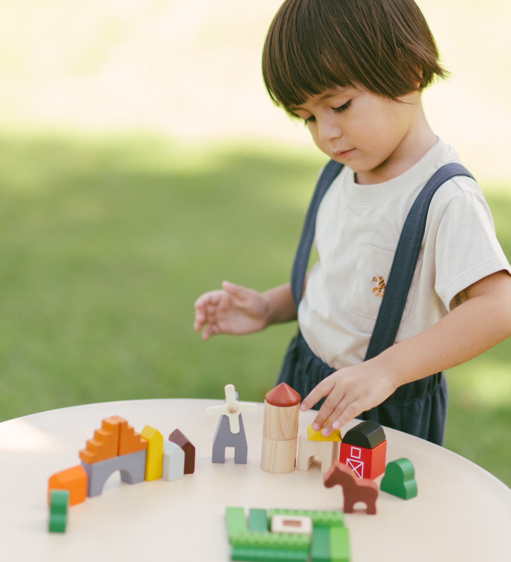 A child playing with the PlanToys Wooden Country Blocks. 