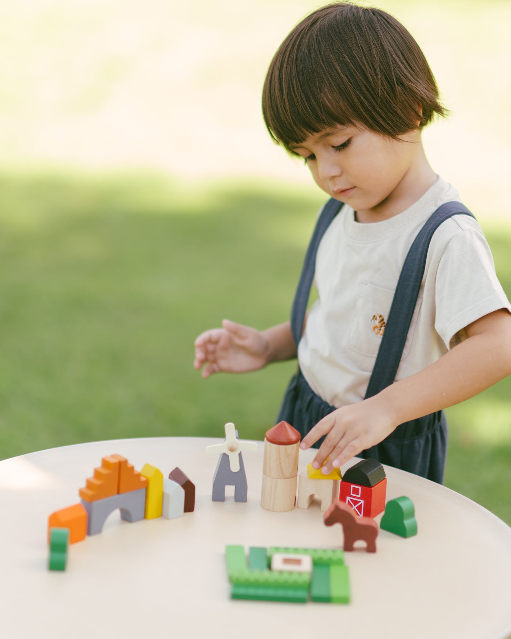 A child playing with the PlanToys Wooden Country Blocks. 