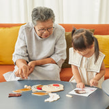 Woman and young girl playing with the PlanToys wooden build a face toy set on a wooden table