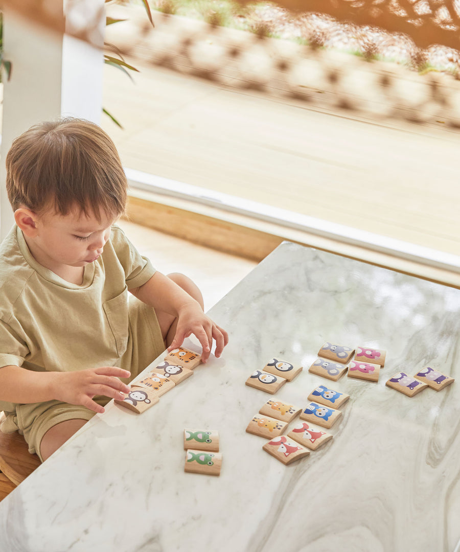 A child sitting at a white marble table playing with the PlanToys Matching Animals Memory Game. 