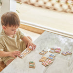 A child sitting at a white marble table playing with the PlanToys Matching Animals Memory Game. 