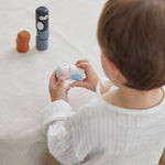 Young boy stacking pieces from the PlanToys wooden animal matching figures on a white table