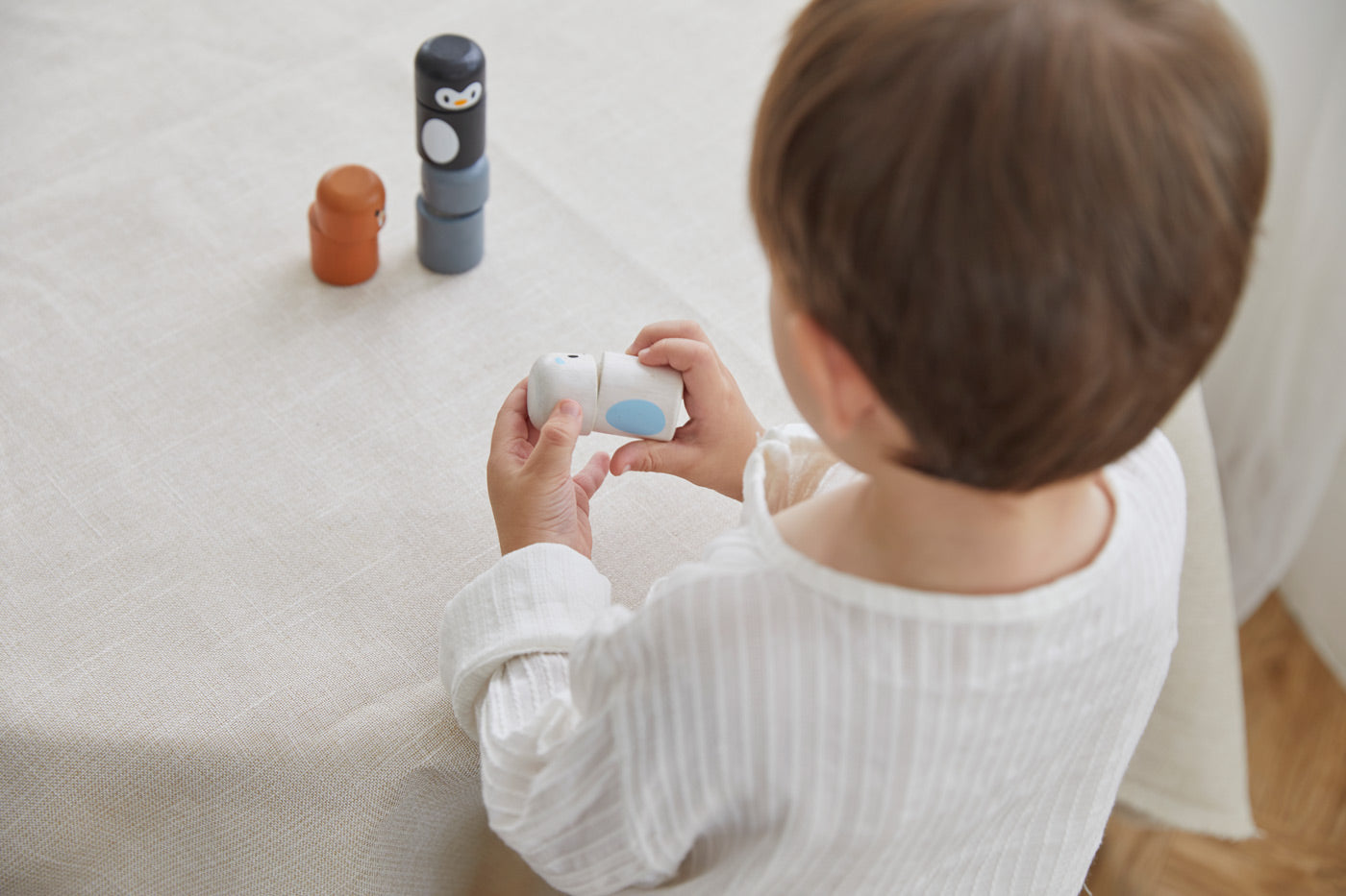 Young boy stacking pieces from the PlanToys wooden animal matching figures on a white table