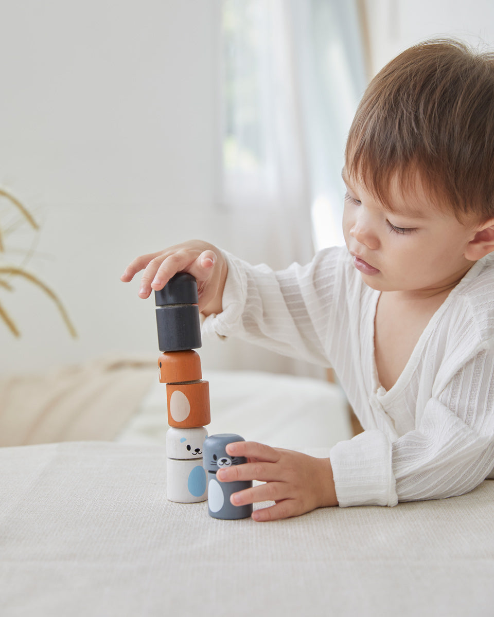 Young boy playing with the PlanToys wooden arctic animal peg dolls on a white table