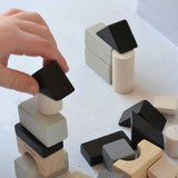 A close up of a child's hand laying with the blocks from the Plan Toys Mini Construction Set.