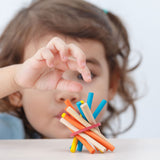 A close up of child's hands in the pincer grip position reaching for a blue stick from the PlanToys Mini Pick-Up Sticks.
