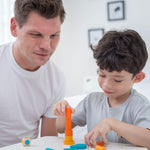 An adult and a child sitting at a table playing with the PlanToys Mini Stacking Game.