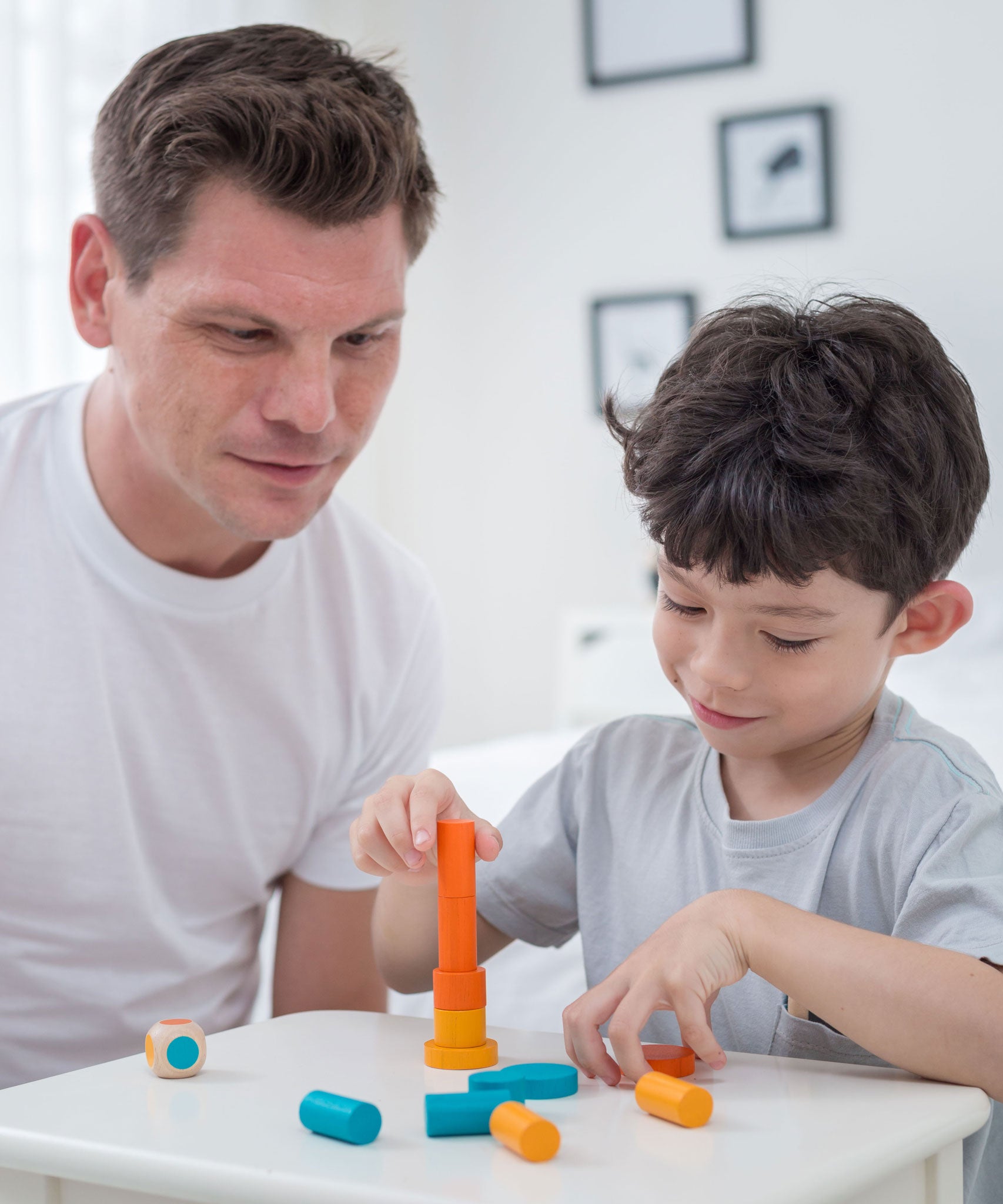 An adult and a child sitting at a table playing with the PlanToys Mini Stacking Game.