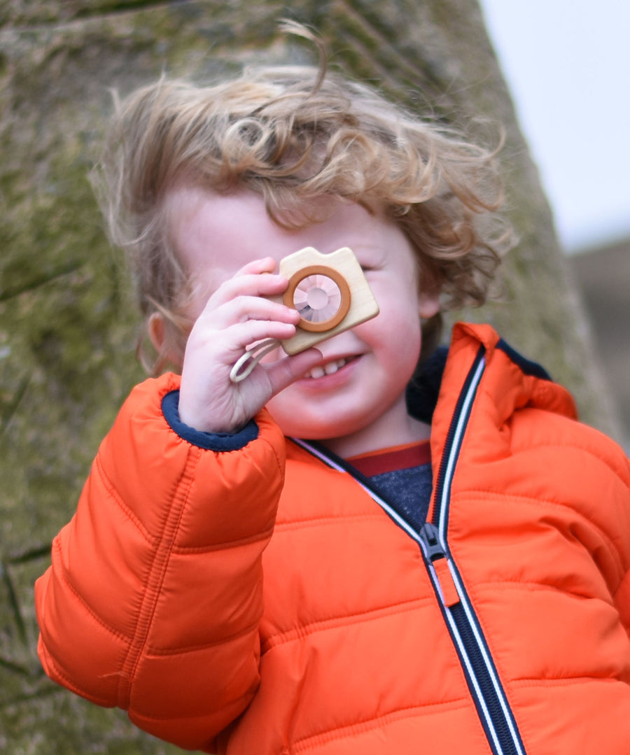 A child holding up the PlanToys Camera in front of their face. 