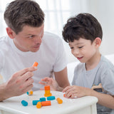 An adult and a child sitting at a table playing with the PlanToys Mini Stacking Game.