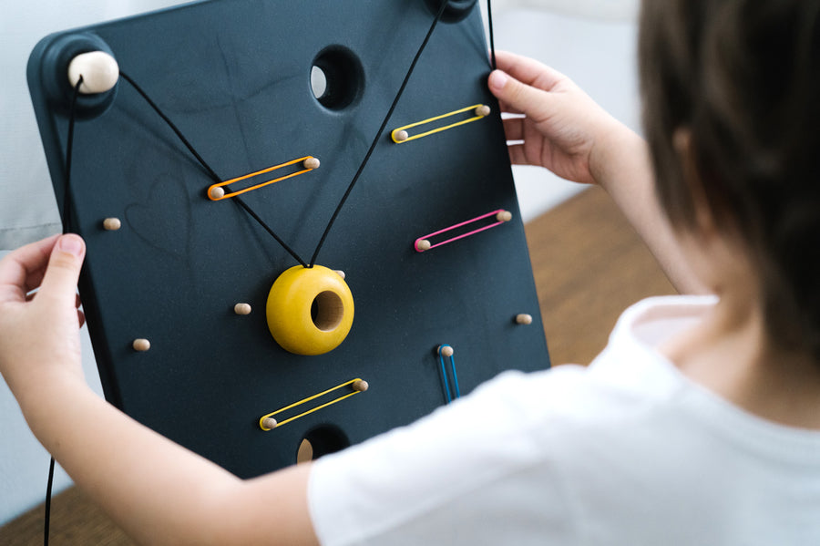 Close up of a child playing with the PlanToys wooden wall ball board game