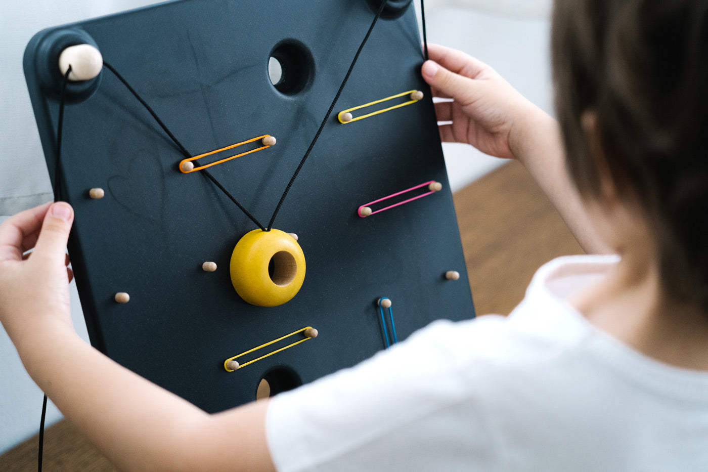 Close up of a child playing with the PlanToys wooden wall ball board game