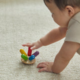 Close up of young child spinning the PlanToys flexi jellyfish toy around on a beige carpet