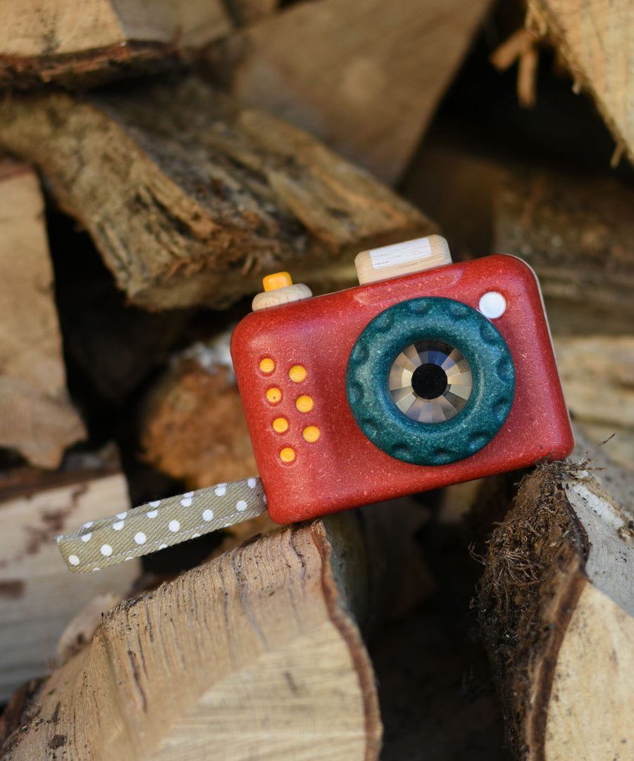 The Plan Toys My First Camera placed on a pile of logs