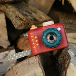 The Plan Toys My First Camera placed on a pile of logs