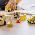 A close up of a child playing with the PlanToys Road Construction Set.