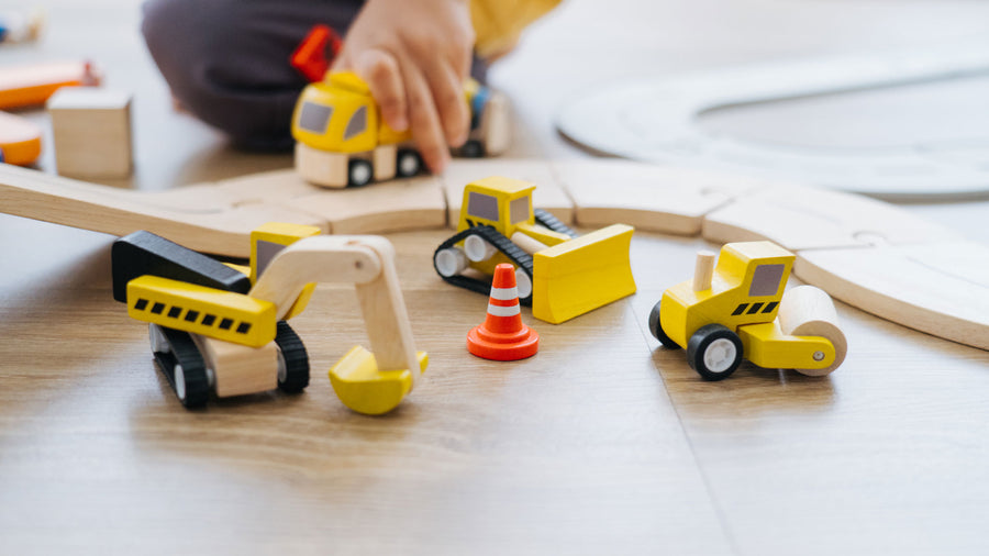 A close up of a child playing with the PlanToys Road Construction Set.