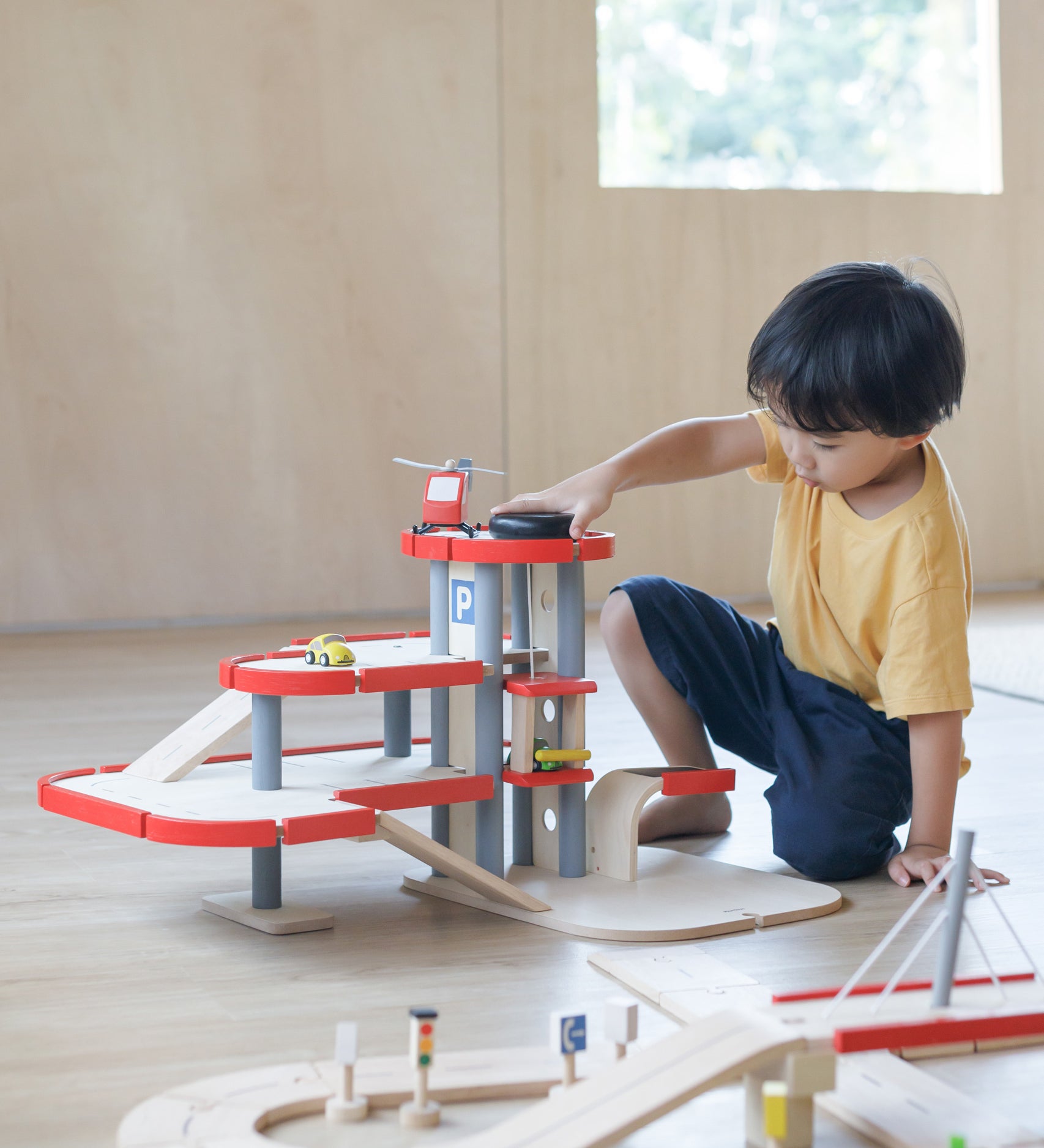 A child playing with the PlanToys PlanWorld Parking Garage.