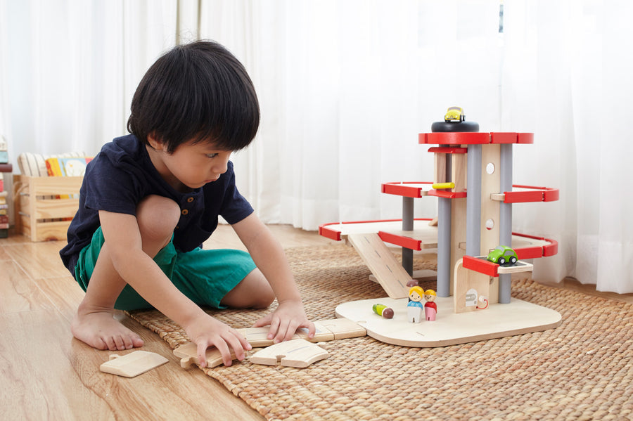 A child playing with the PlanToys PlanWorld Parking Garage.