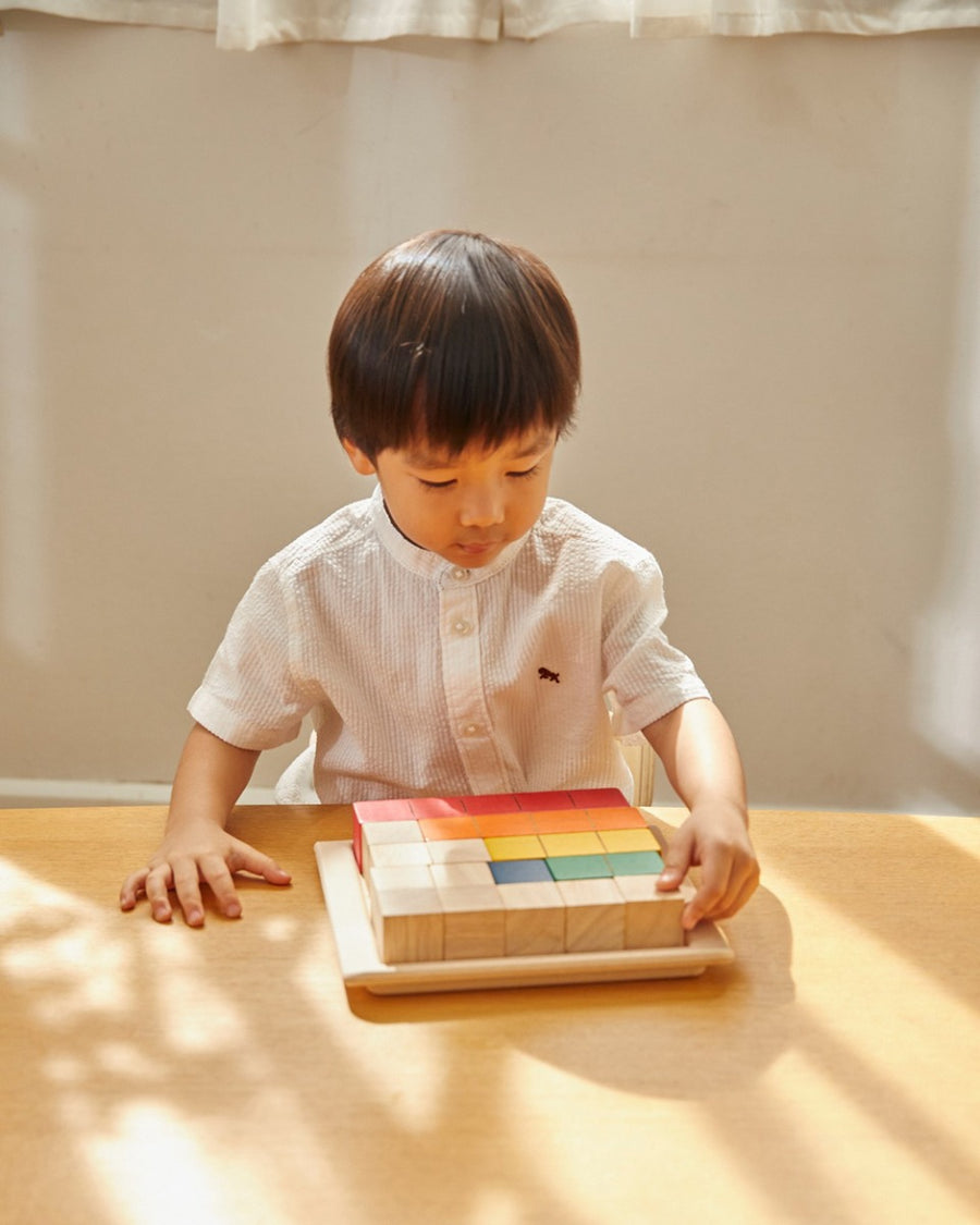 Young boy sorting the PlanToys coloured counting cube blocks on a wooden table