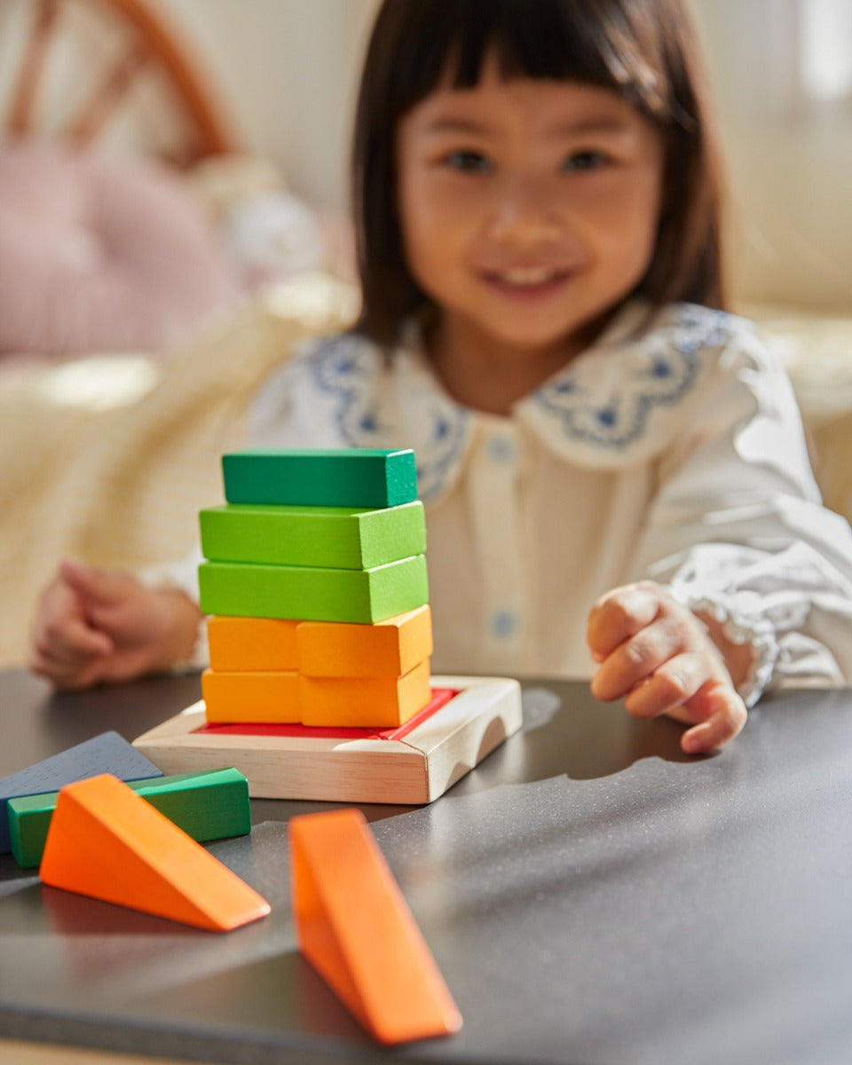 Close up of girl making a stack with the PlanToys plastic-free fraction blocks set