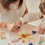 Close up of mother and daughter playing with the PlanToys wooden Mandala set on a white table