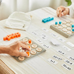 Close up of 2 people playing with the PlanToys wooden maths learning bingo game