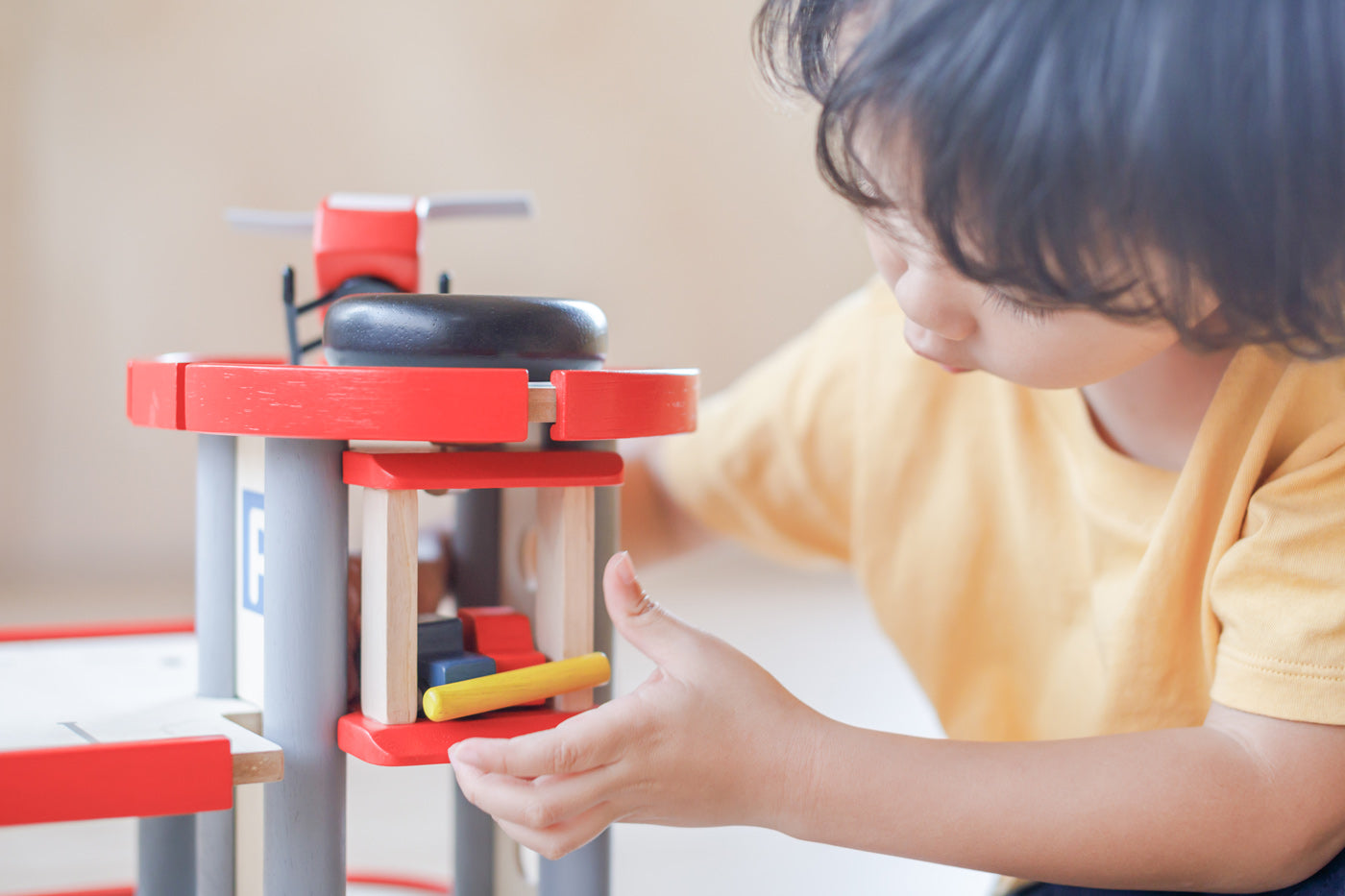 A close up of a child playing with the PlanToys PlanWorld Parking Garage.