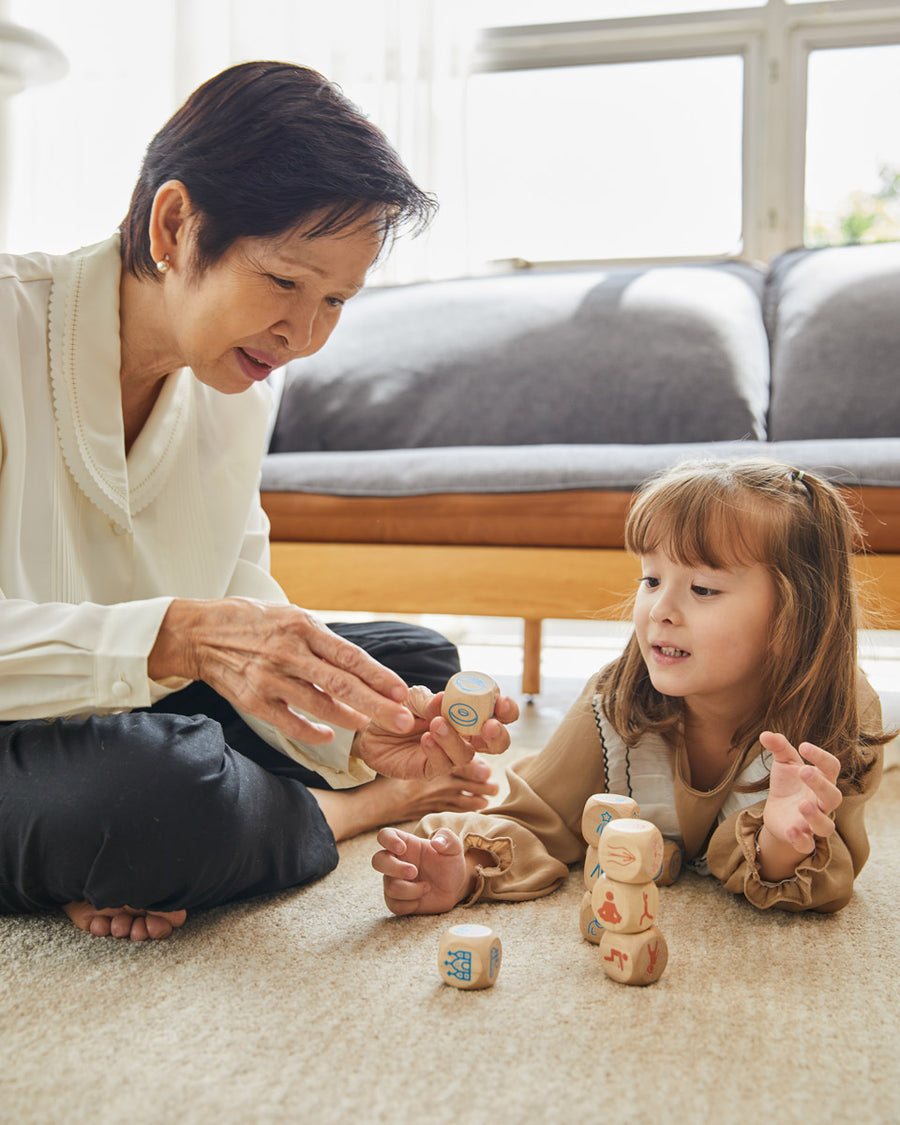 Woman and girl on the floor playing with the PlanToys wooden storytelling dice set