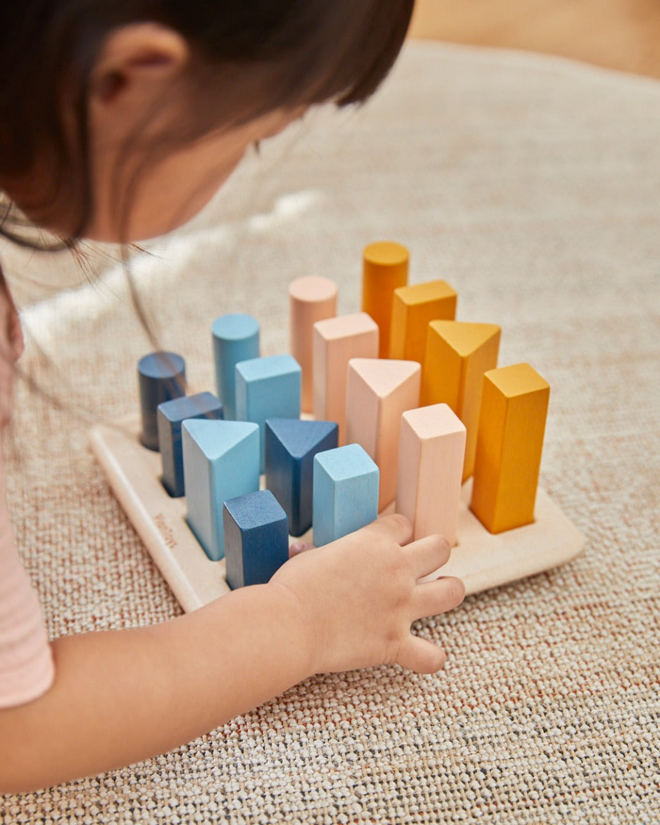 Close up of young child playing with the PlanToys plastic-free wooden geometric peg board