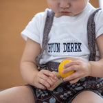 A child looking in concentration whilst putting in Yellow PlanToys Wooden Nuts and Bolts Puzzle Ball bolt into a wooden block.