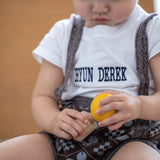 A child looking in concentration whilst putting in Yellow PlanToys Wooden Nuts and Bolts Puzzle Ball bolt into a wooden block.