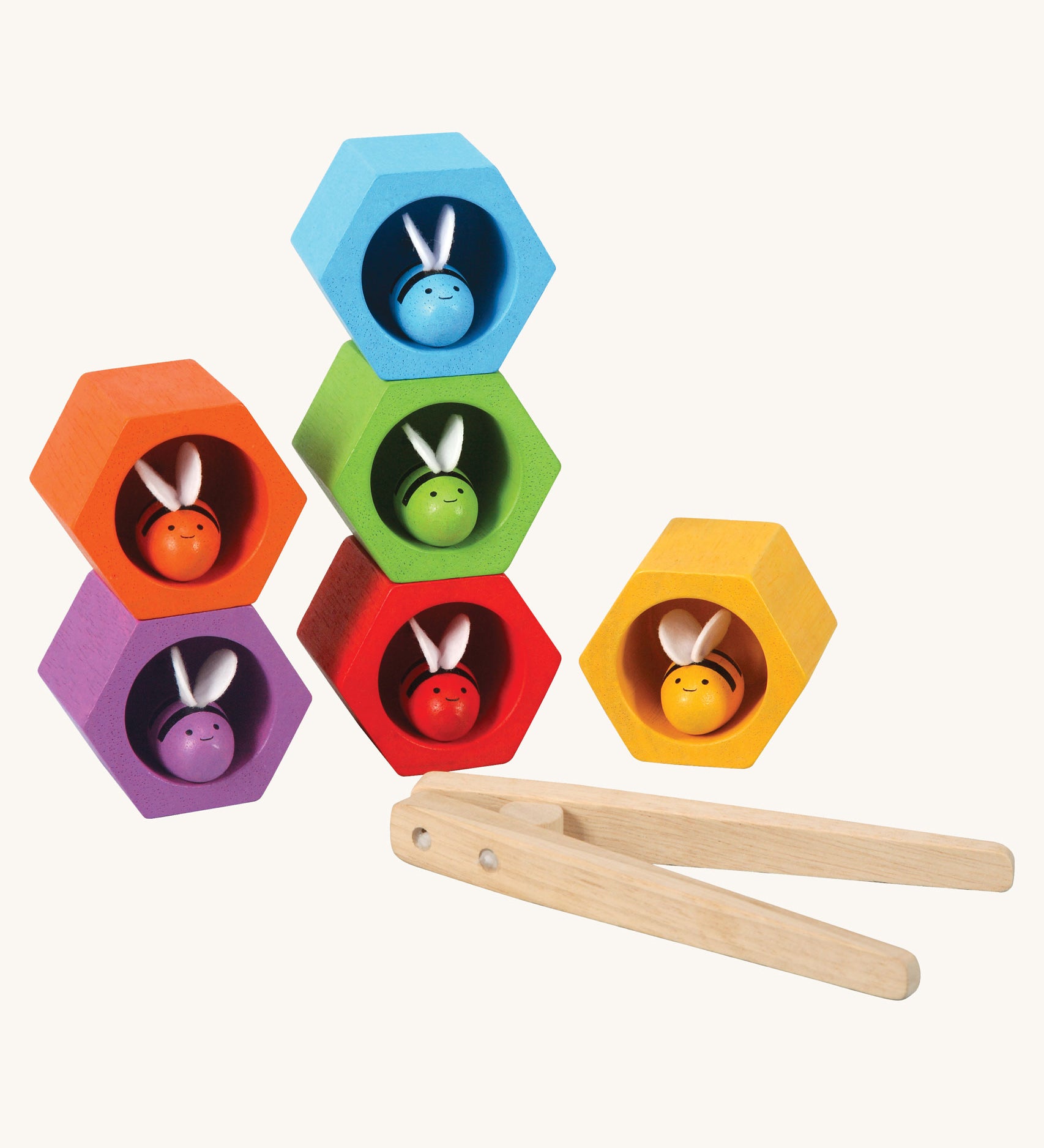 The PlanToys Bee Hives in the Rainbow colour way on a plain background. The bees are all in their matching coloured bee hive. The wooden tweezers can be seen placed in front of the hives. 
