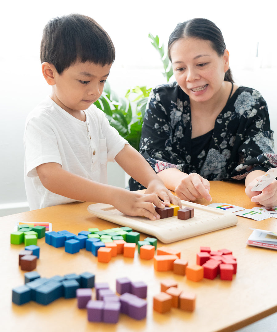 A child and an adult playing with the PlanToys 100 Rainbow Counting Cubes.