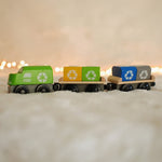 The PlanToys Recycling Train Toy placed on a fluffy surface in front of fairy lights.