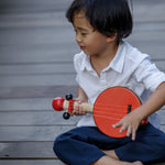 A child playing with the PlanToys Wooden Toy Banjo.