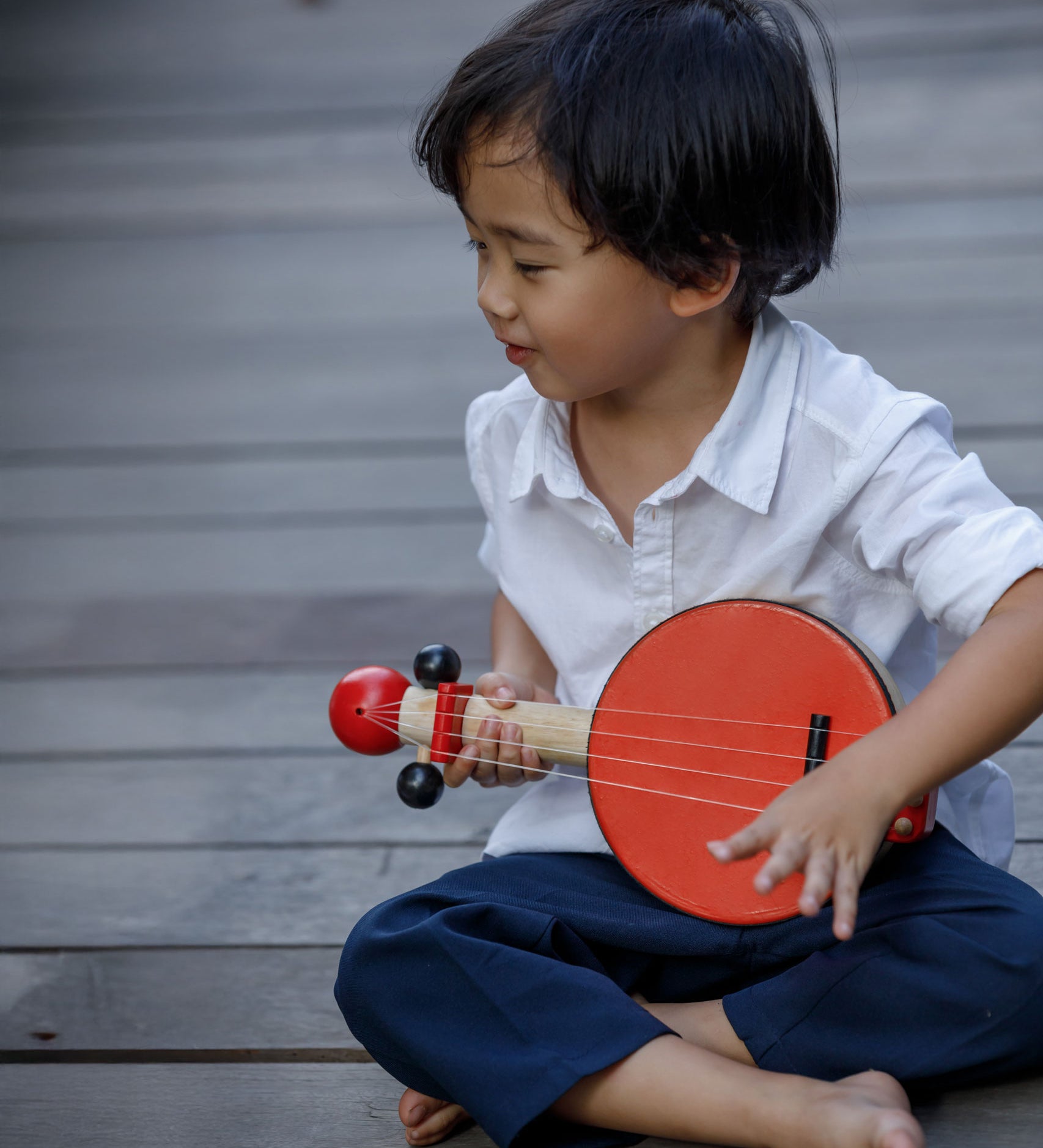 A child playing with the PlanToys Wooden Toy Banjo.