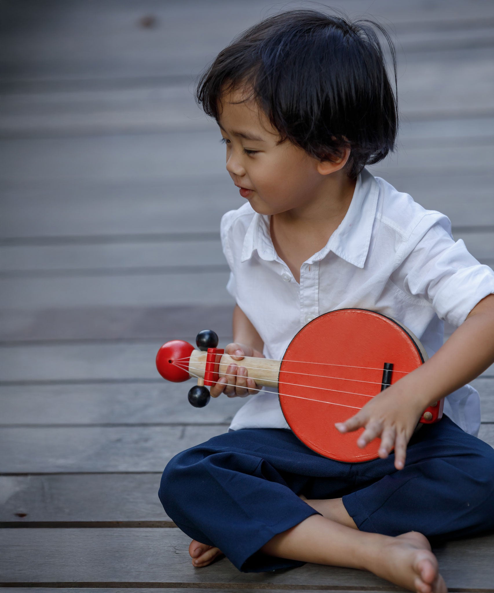 A child playing with the PlanToys Wooden Toy Banjo.