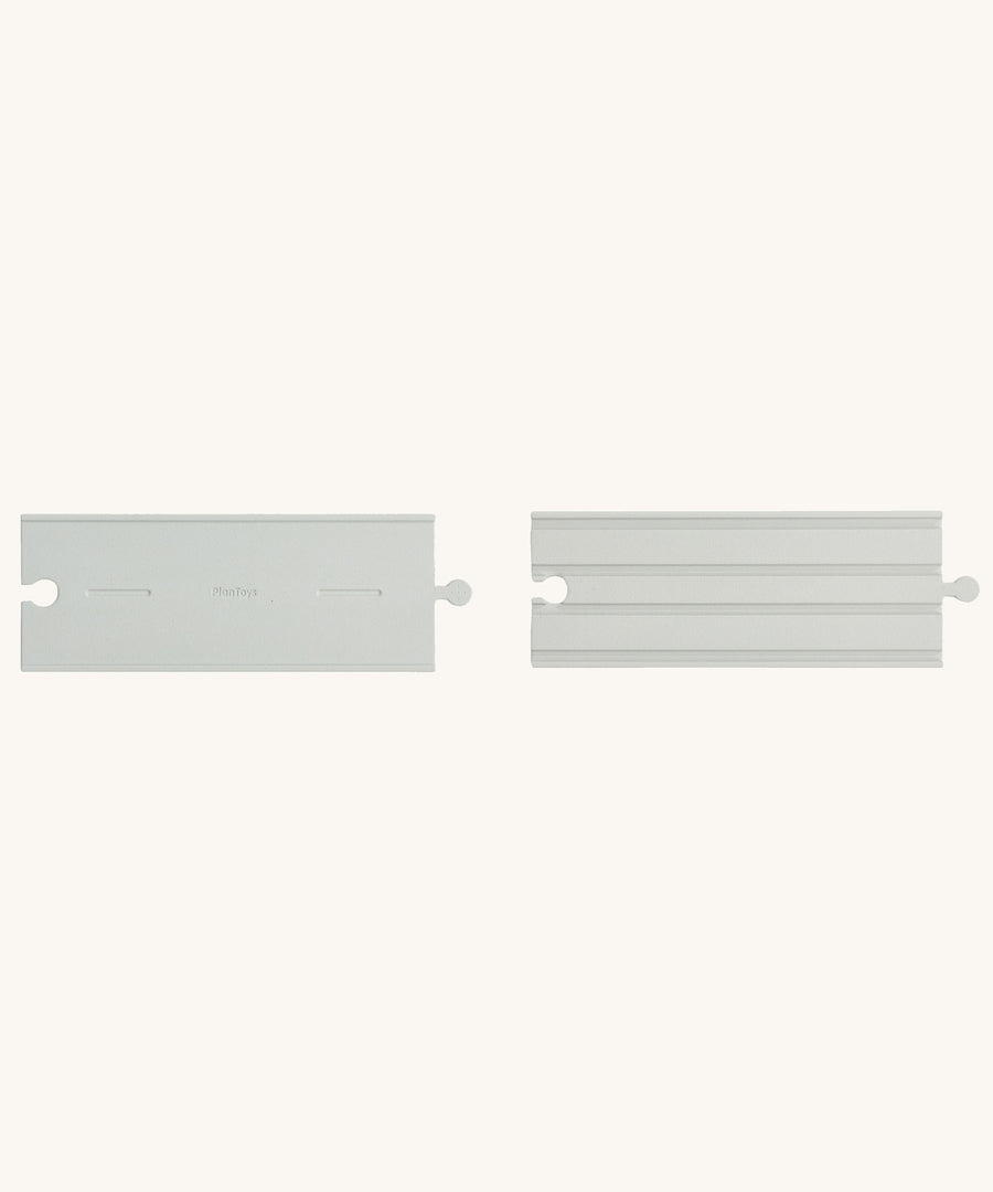 Two pieces from the PlanToys Rubber Road and Rail Straights Extension Set on a plain background. 
