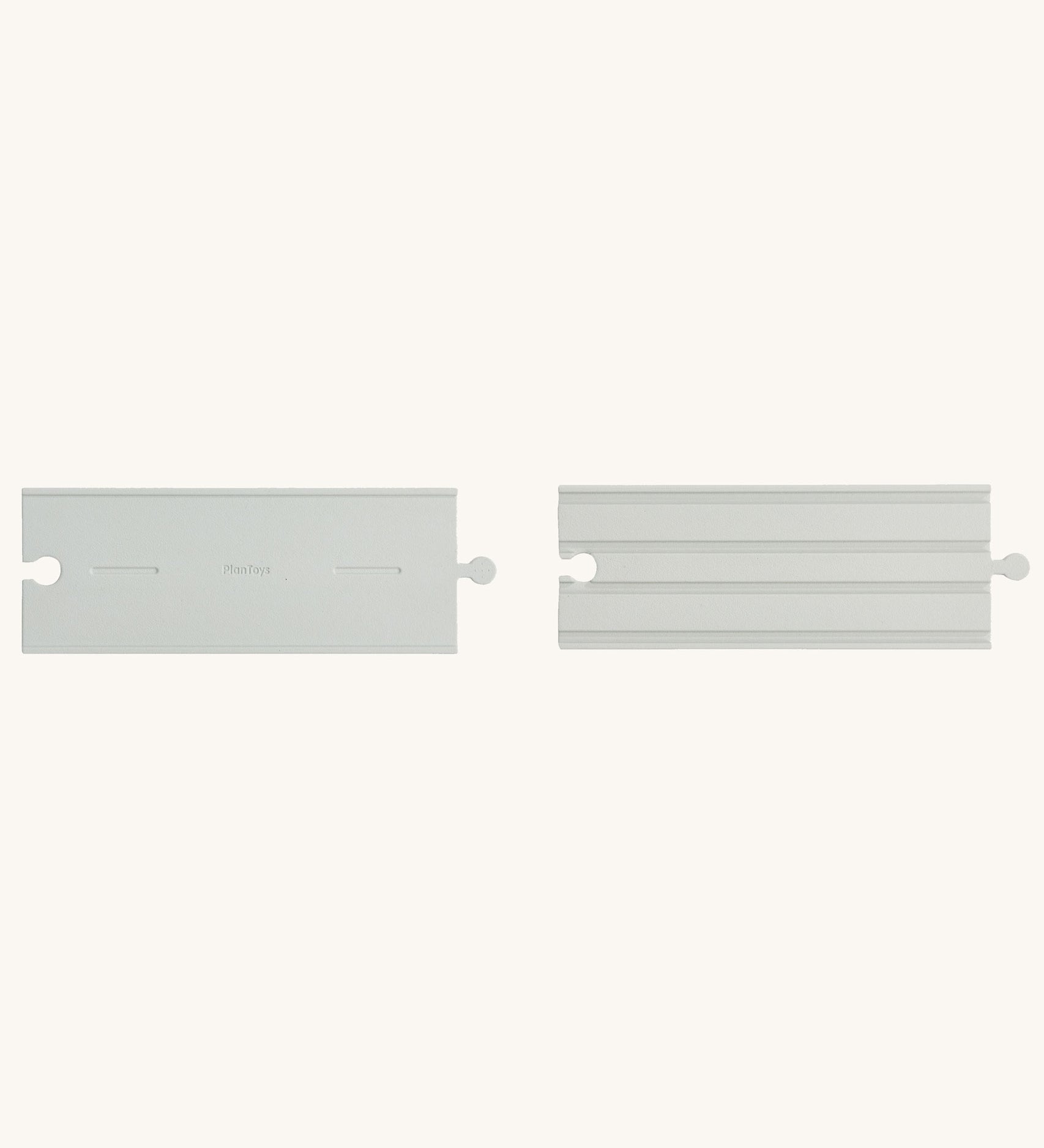 Two pieces from the PlanToys Rubber Road and Rail Straights Extension Set on a plain background. 
