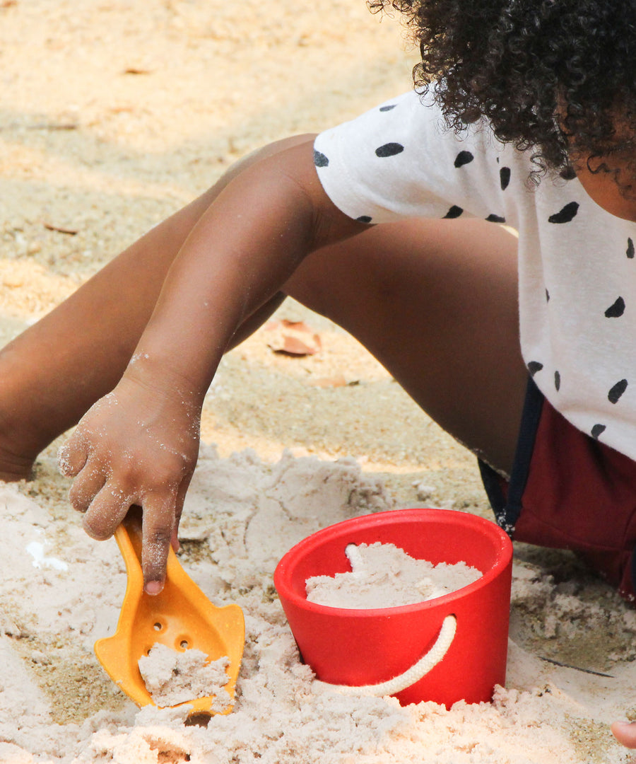 A child playing with the yellow toll from the PlanToys Sand Play Set. 