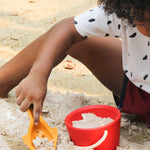 A child playing with the yellow toll from the PlanToys Sand Play Set. 