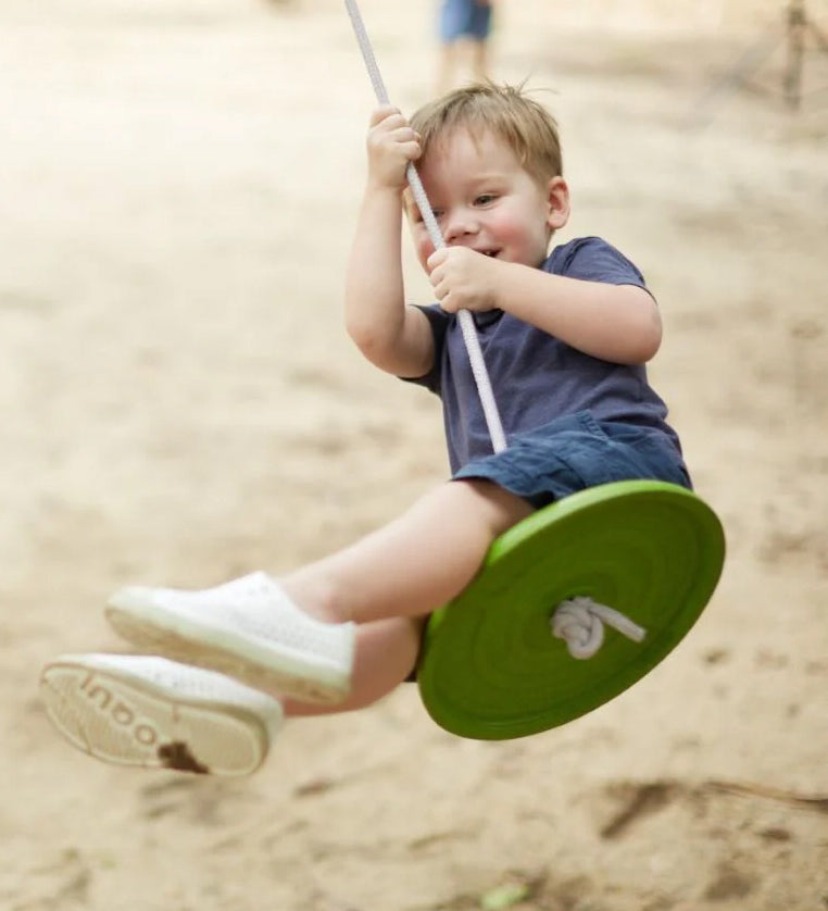 Child swinging outside on the PlanToys Saucer Disc Swing. 