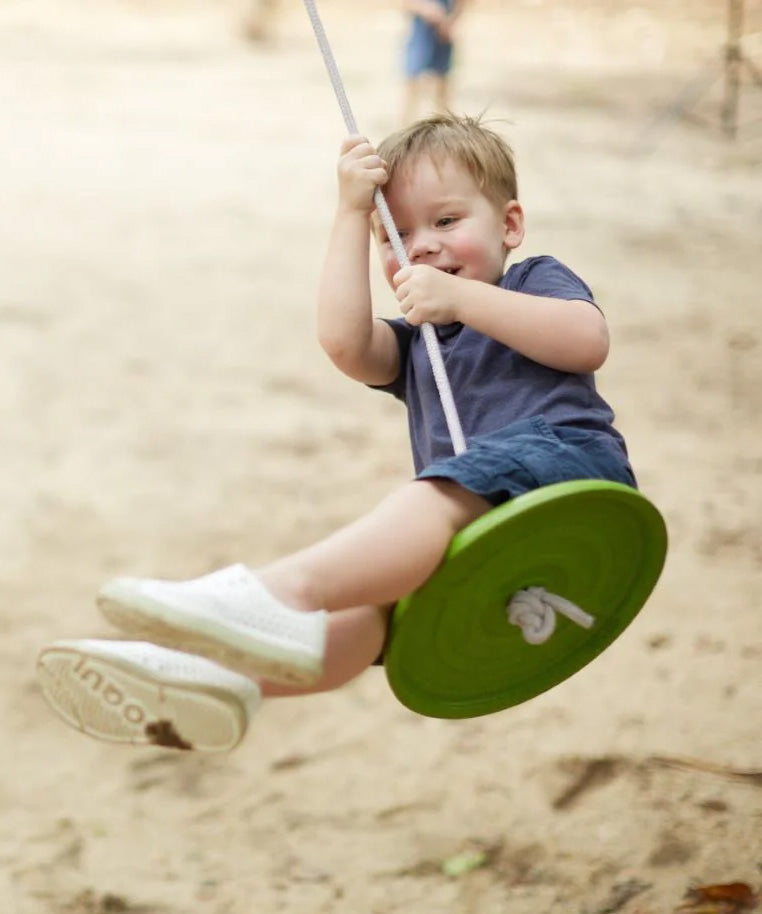 Child swinging outside on the PlanToys Saucer Disc Swing. 