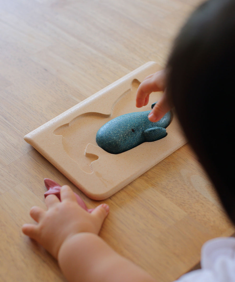 PlanToys Sea Life Puzzle with the pieces shown in the puzzle base on a wooden table. 