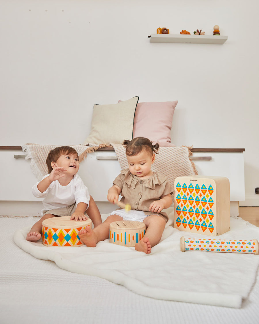 2 children sat on the floor playing with the PlanToys plastic-free wooden musical toys