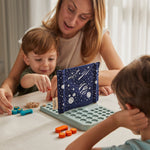 Children with an adult sitting by a table playing with the PlanToys Guess My Planet Game. 